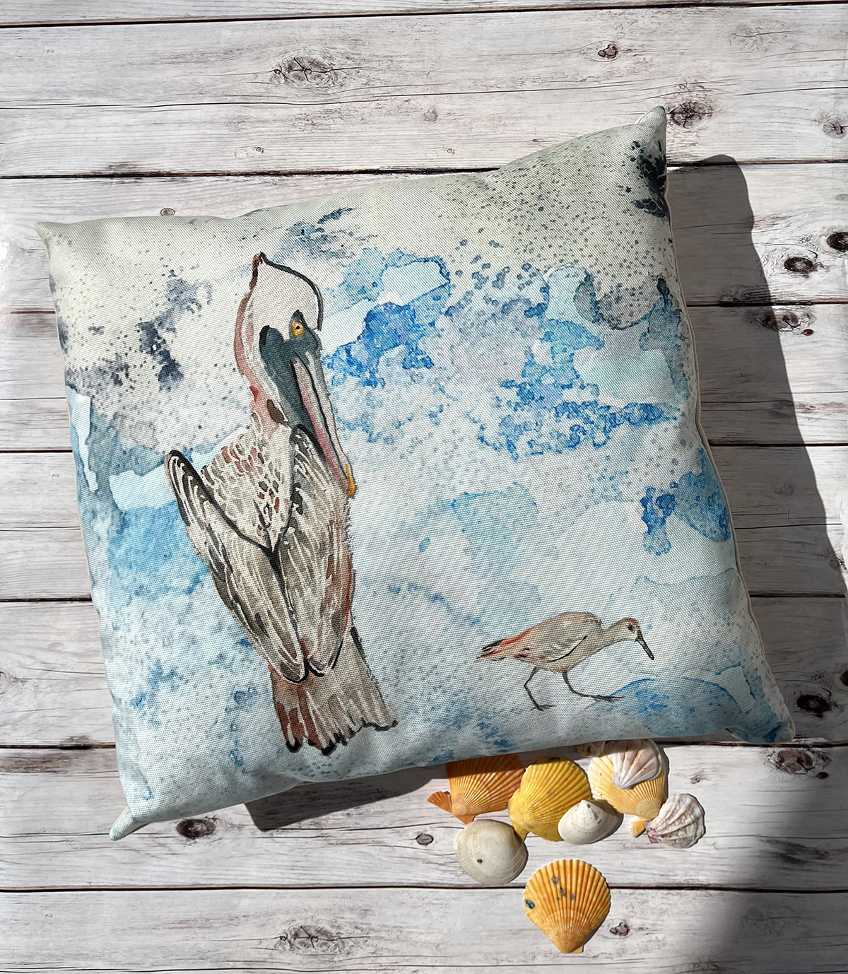 This coastal outdoor throw pillow cover features a pelican watercolor with a background that was created using a salt technique. These handmade throw pillow covers are handcrafted by Hibiscus Jazz artist Ali Norton.